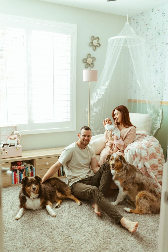 Paradise Valley newborn photographer capturing family cuddling newborn baby girl with Australian Shepherd dogs in cozy Arizona home