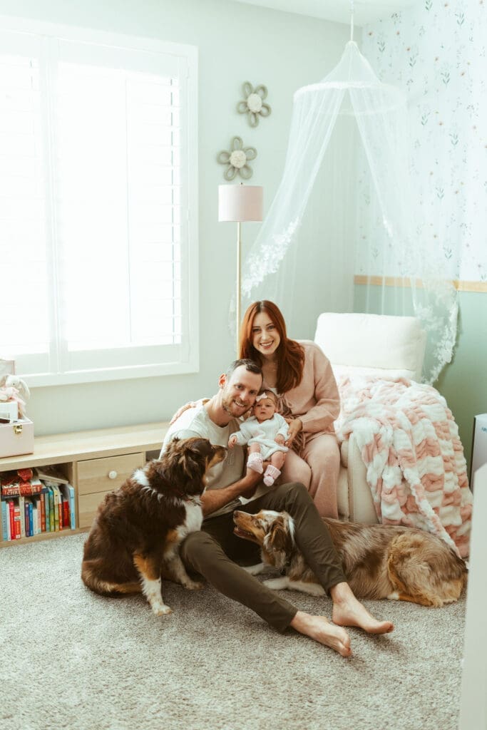 Paradise Valley newborn photography session with parents holding newborn baby girl near floral wallpaper nursery wall