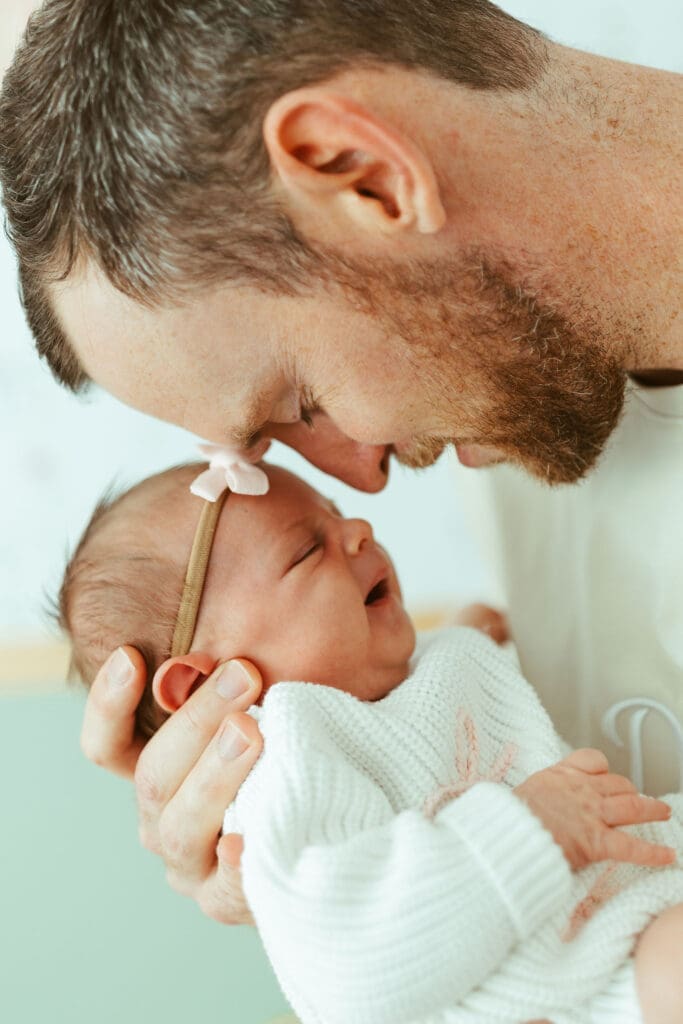 Paradise Valley newborn photography session with parents holding newborn baby girl near floral wallpaper nursery wall