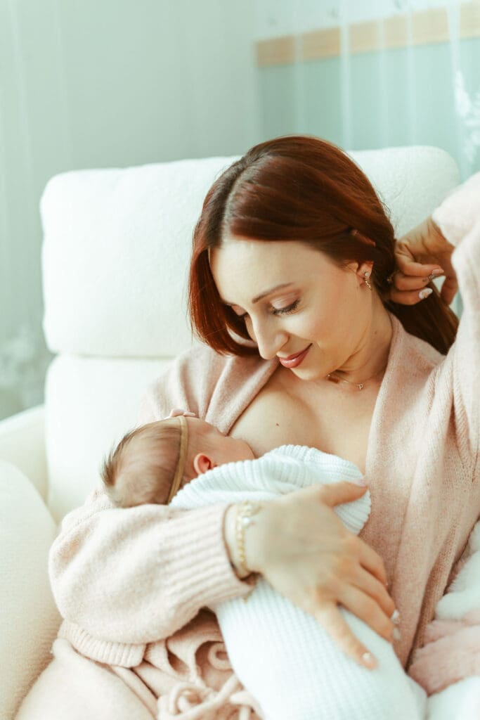 Arizona newborn photography with mother rocking baby girl in blush nursery chair during relaxed lifestyle newborn session
