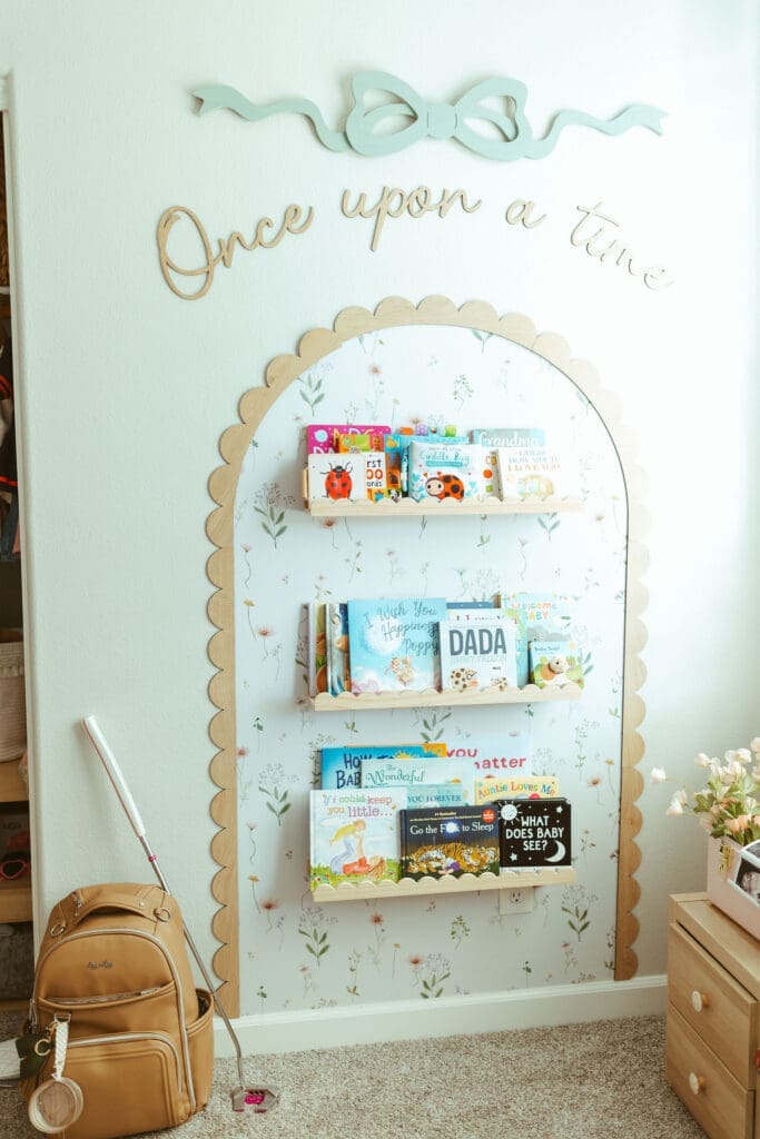 Scottsdale Arizona newborn photographer capturing mother holding sleeping baby girl beside floral nursery wallpaper during in-home lifestyle session