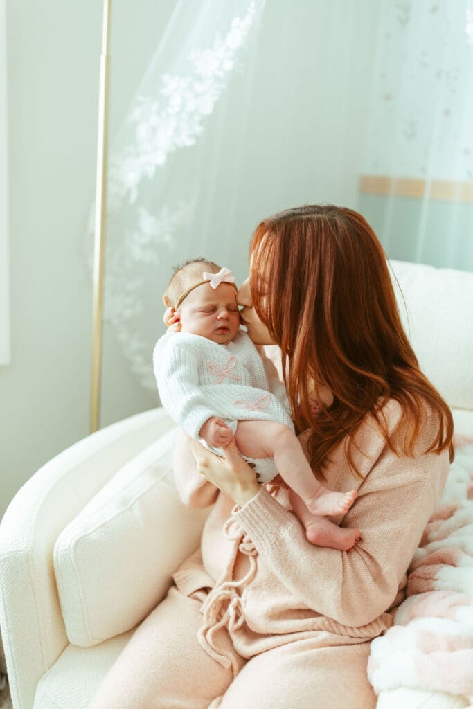 Mother holding newborn baby girl in blush nursery during in-home lifestyle newborn photography session in Paradise Valley Arizona