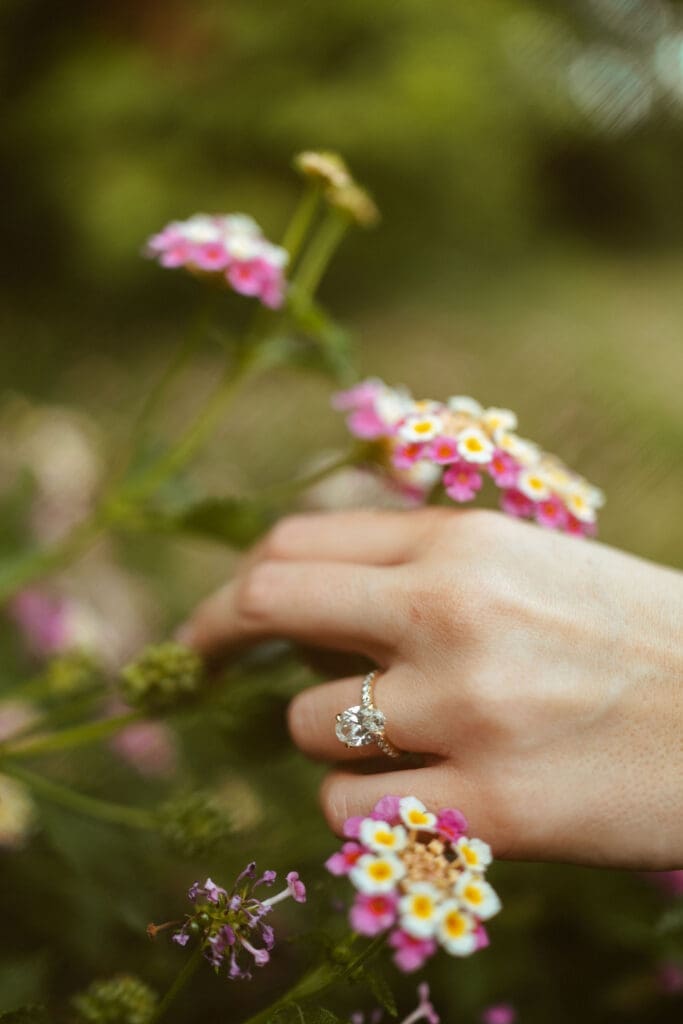 close up of engagement ring, Arizona engagement photography featuring engaged couple kissing near rustic picnic table surrounded by greenery and sunset light