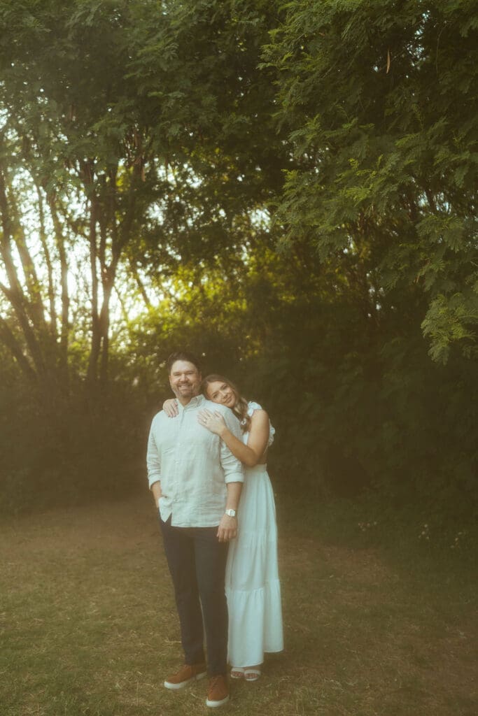Arizona engagement session featuring couple twirling in grassy field with soft haze and glowing sunset backlight