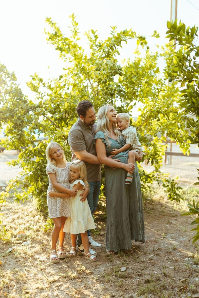 Family maternity photography featuring expecting parents and three children celebrating pregnancy in Queen Creek Arizona citrus grove