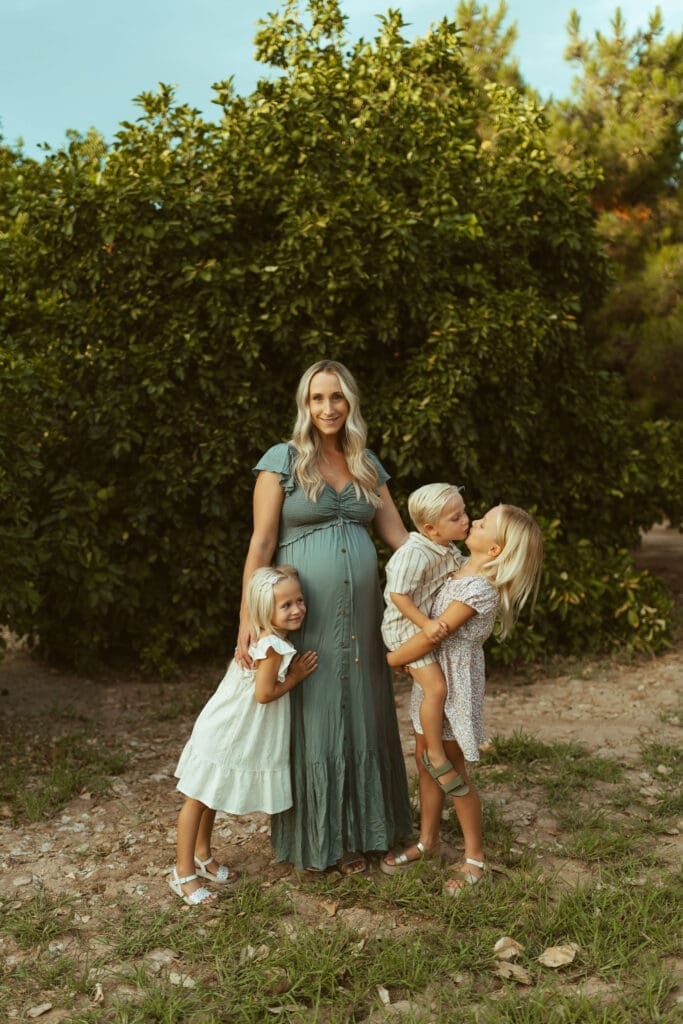 Phoenix maternity photographer capturing pregnant mother with three children during family maternity session at Hagen Farms in Queen Creek Arizona