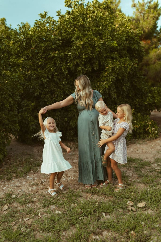 Pregnant mother twirling daughter during playful family maternity session at Hagen Farms near Phoenix Arizona