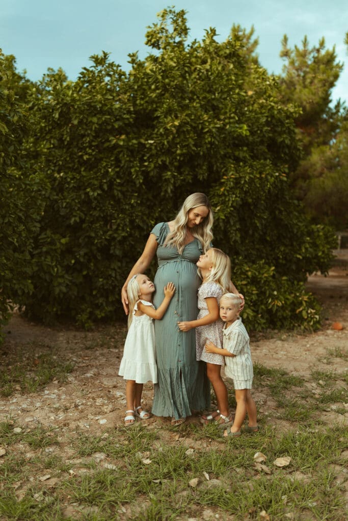 Queen Creek maternity photographer capturing siblings hugging pregnant mother during family maternity photos at Hagen Farms