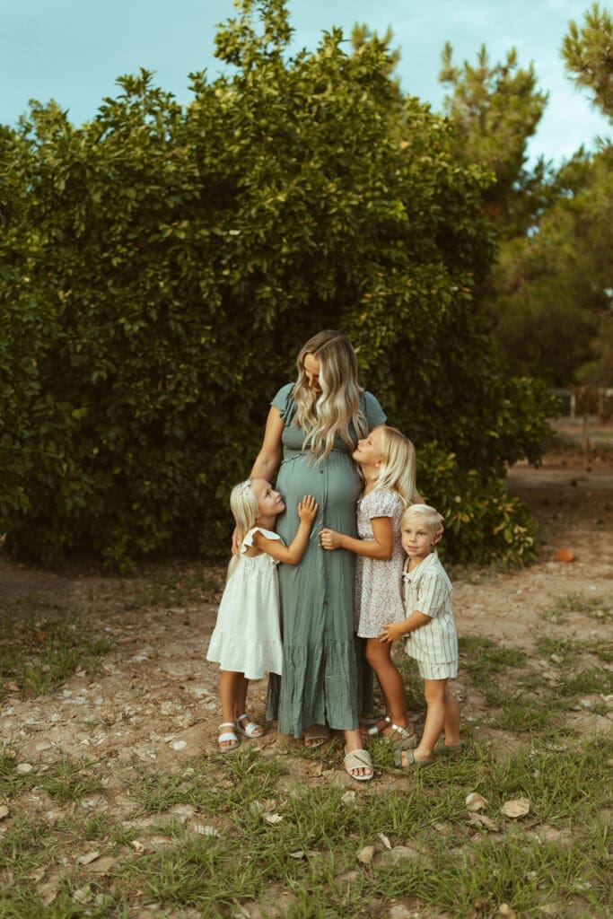 Arizona family maternity photographer documenting siblings celebrating new baby during outdoor maternity photos in Queen Creek