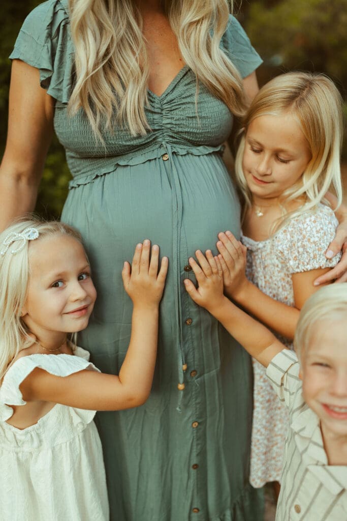 Children touching mother's baby bump during lifestyle maternity photography session in Queen Creek Arizona