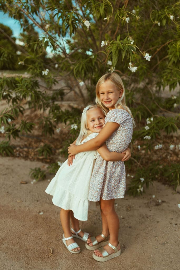 Two sisters hugging during outdoor family maternity session in Queen Creek Arizona citrus grove