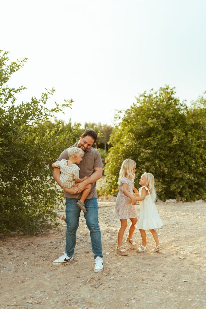 Phoenix maternity photographer capturing father with children during family maternity session at Hagen Farms