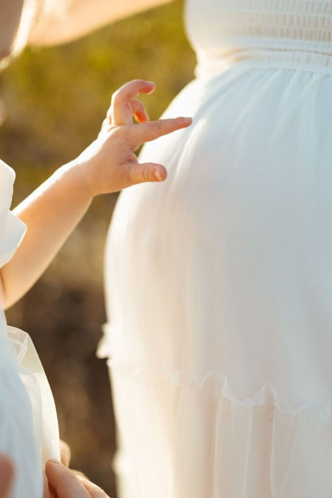 Toddler touching mother's baby bump during outdoor maternity photography session in Mesa Arizona desert near Scottsdale and Phoenix