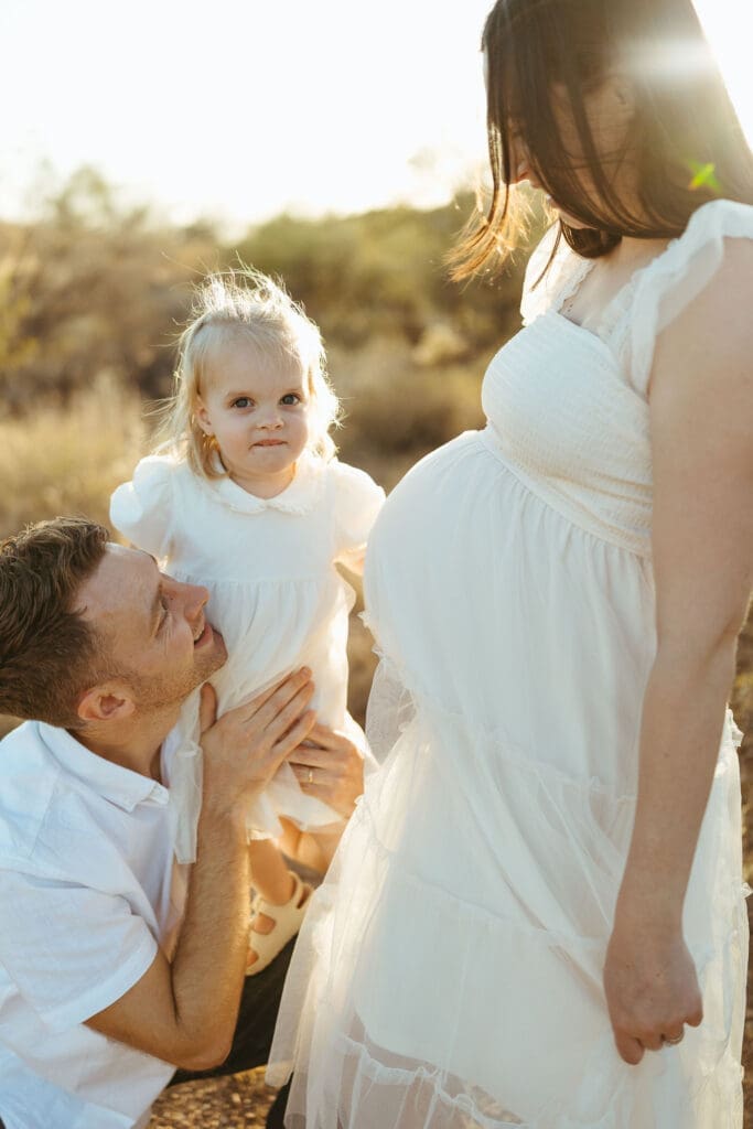 Paradise Valley maternity photography featuring father holding toddler while expecting mother smiles during desert maternity session