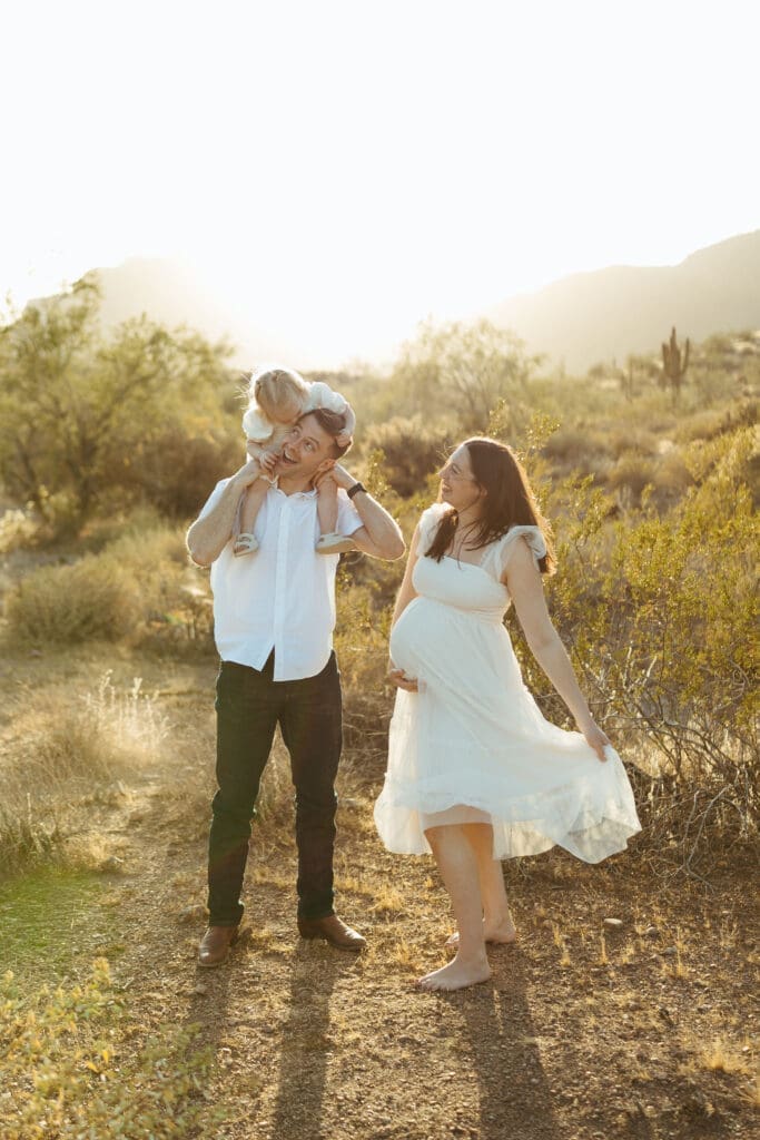 Gilbert maternity photographer capturing family of three walking through Sonoran Desert during golden hour pregnancy photos
