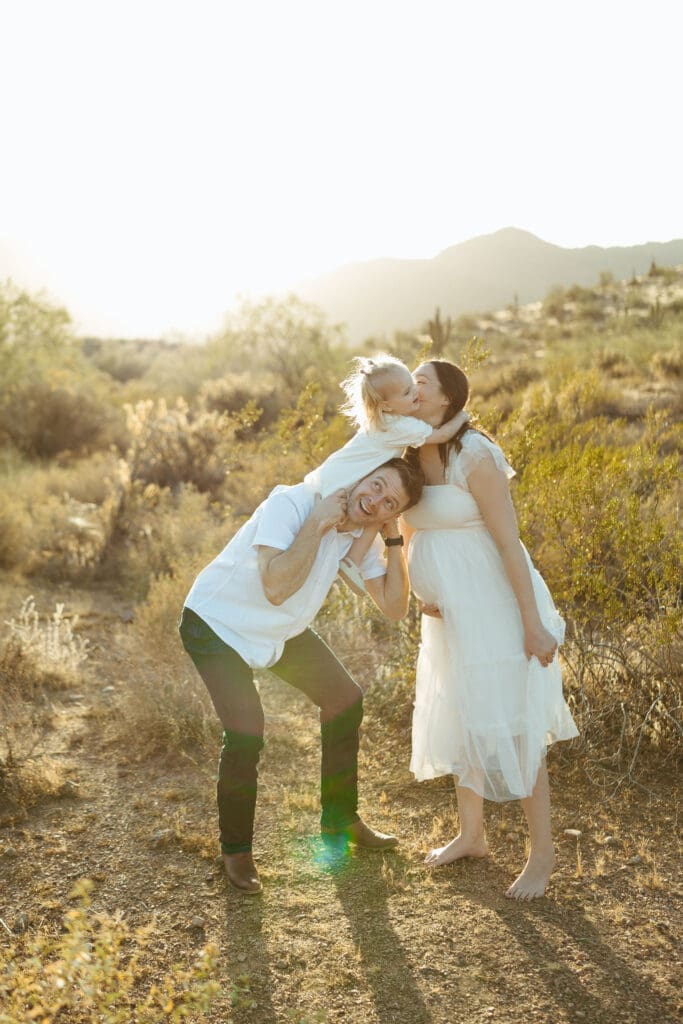 Luxury maternity photography in Arizona featuring toddler hugging expecting mother during sunset desert maternity session