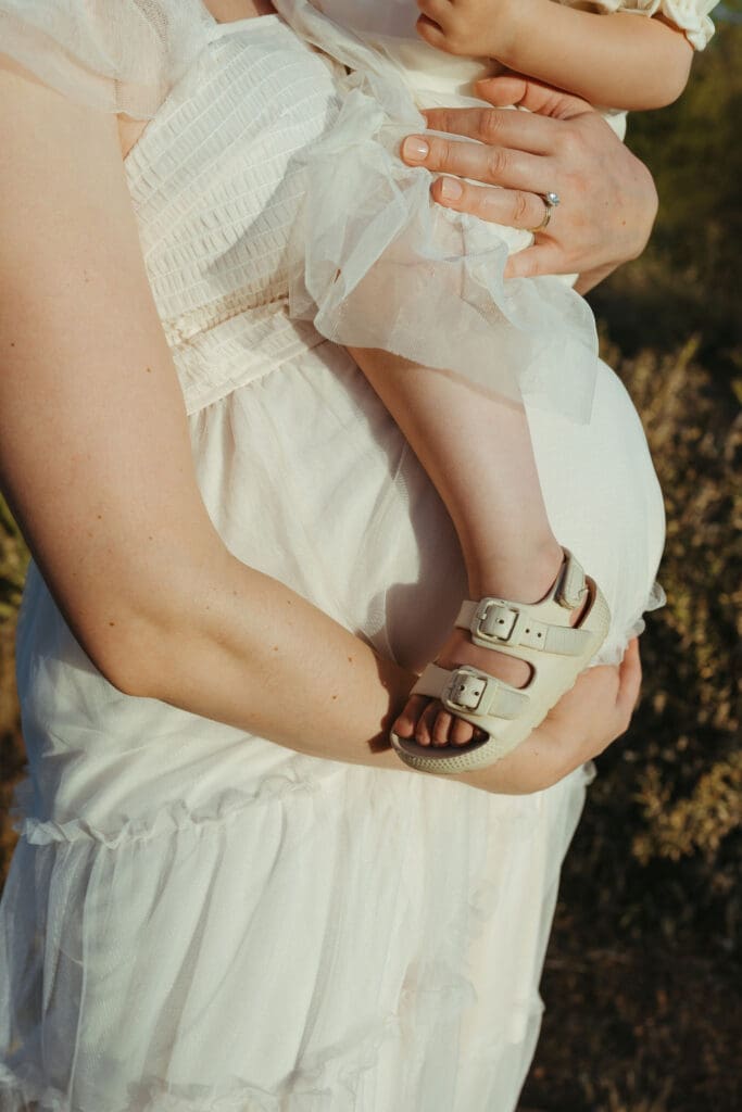 Scottsdale maternity photographer documenting toddler resting on expecting mother's baby bump during Arizona desert maternity photos