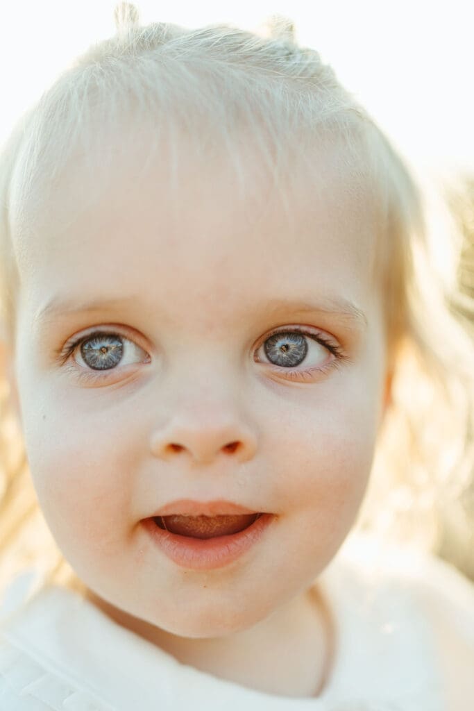 Close-up portrait of blue-eyed toddler during family maternity photography session in Mesa Arizona desert