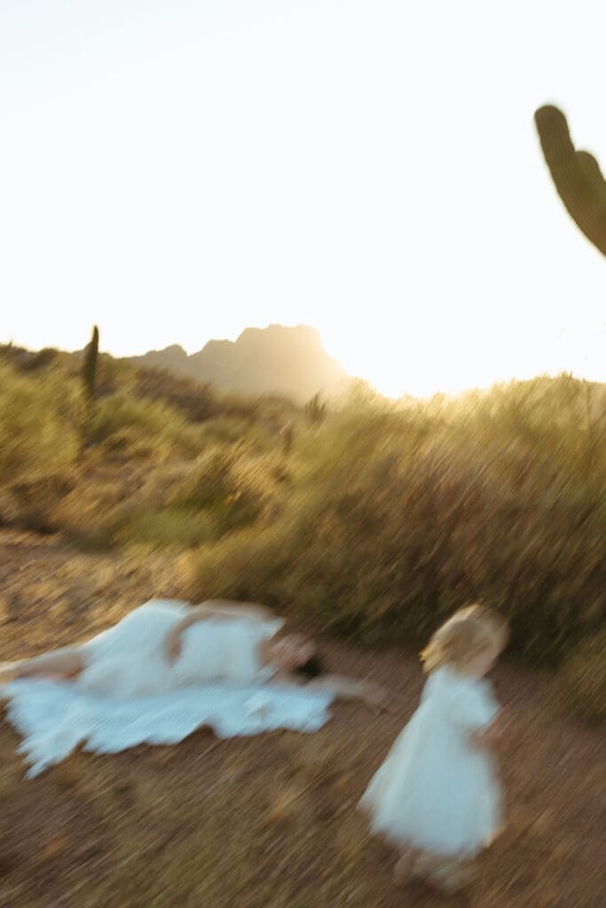 Artistic maternity photography in Mesa Arizona featuring expecting mother and toddler during dreamy motion-blur desert portrait, artsy and creative
