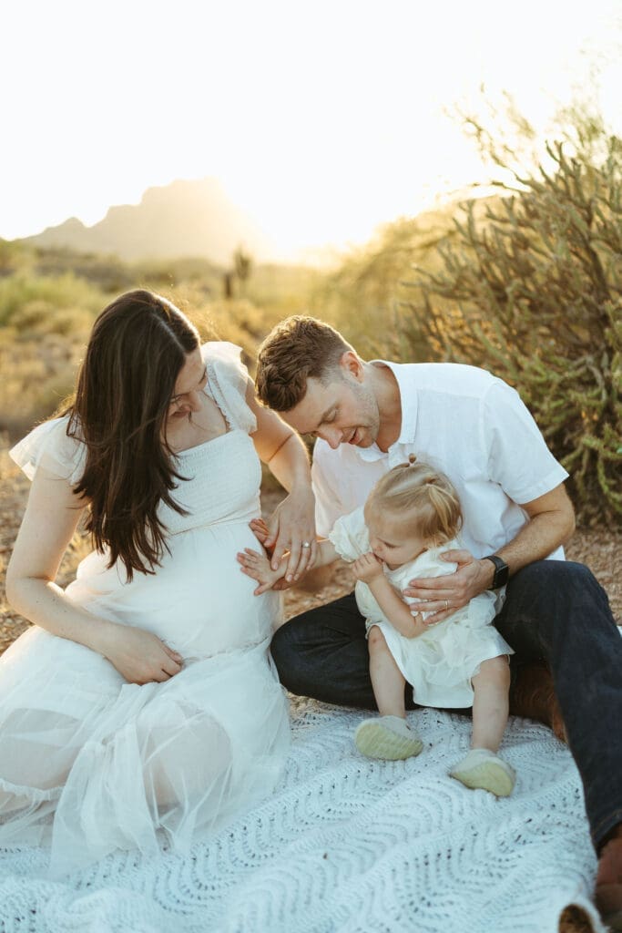 Close-up family maternity portrait featuring toddler touching mother's baby bump during outdoor maternity session near Phoenix Arizona