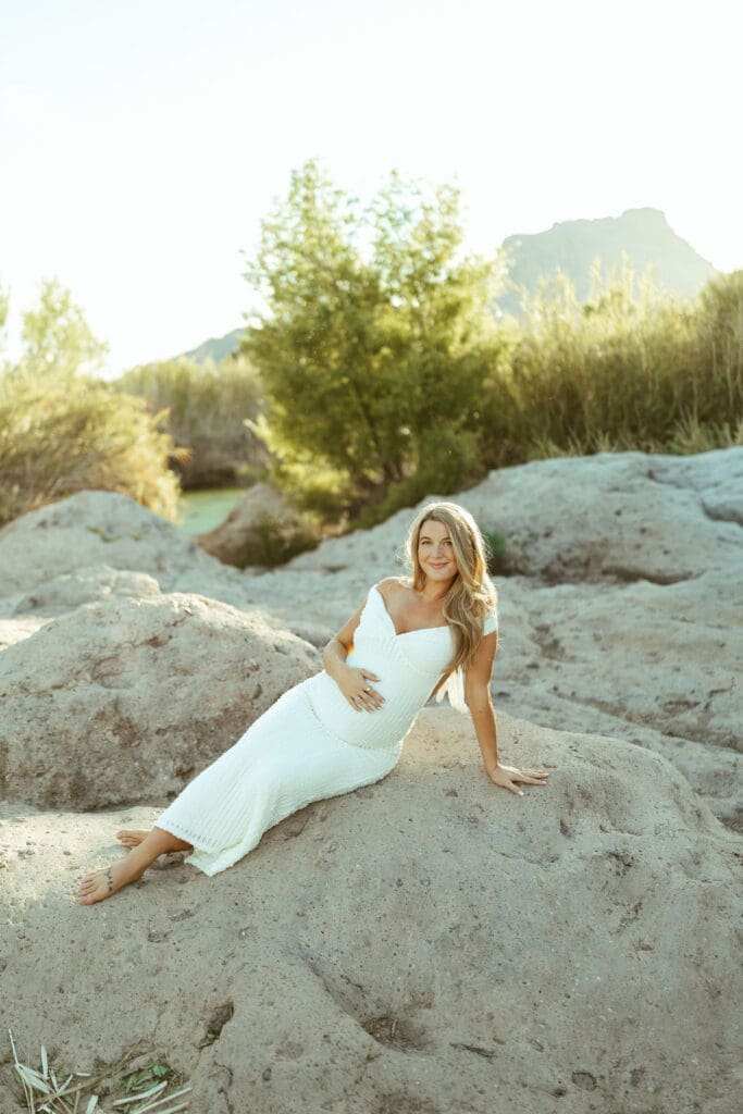 Pregnant couple walking hand in hand along the Salt River during a golden hour maternity session in Mesa Arizona.