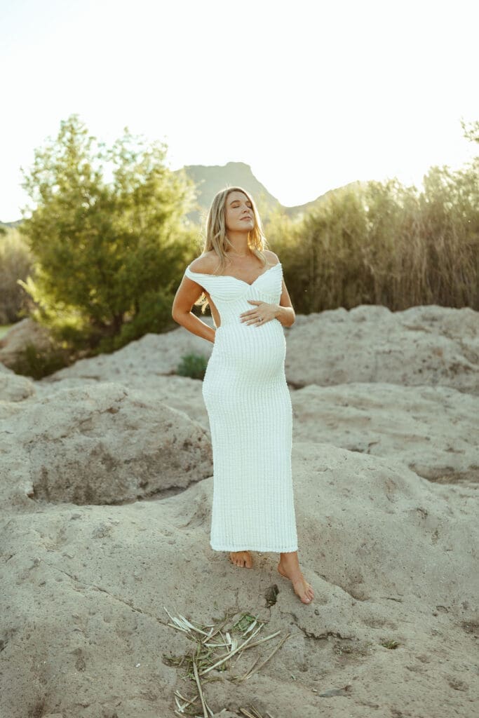 Romantic maternity photos at the Salt River in Arizona with mountain views, soft sunset light, and neutral styling.