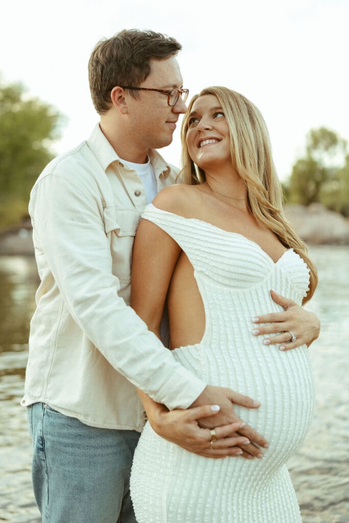 Pregnant woman posing on river rocks during a sunset maternity session at the Salt River in Mesa Arizona.