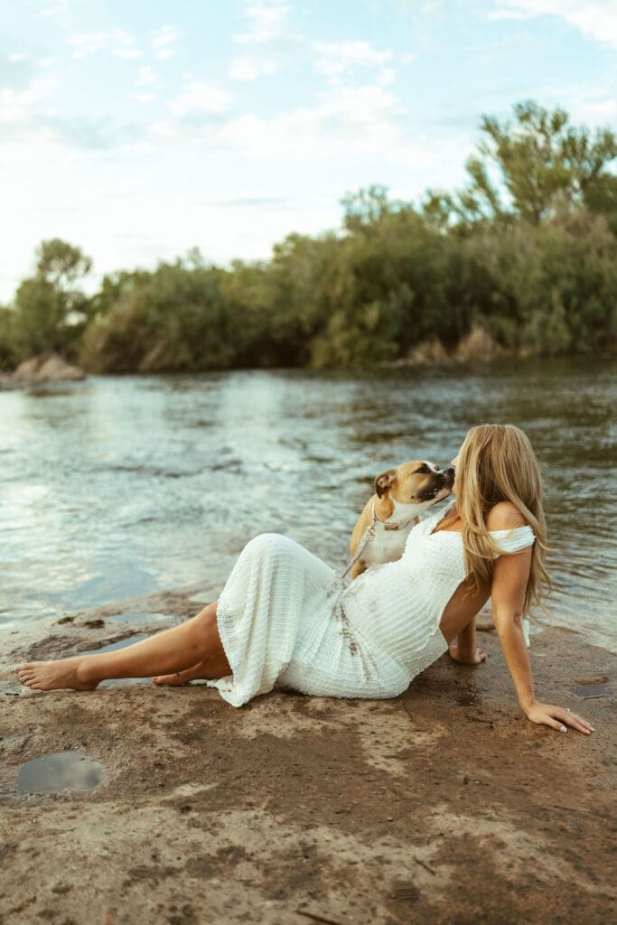 Maternity session with family dog at Phon D Sutton Recreation Area featuring a pregnant mother relaxing beside the river in Arizona.