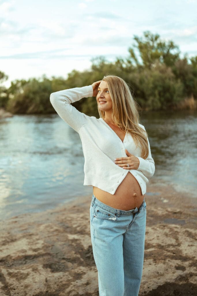 Pregnant woman posing beside the Salt River in Mesa Arizona during a golden hour maternity session.
