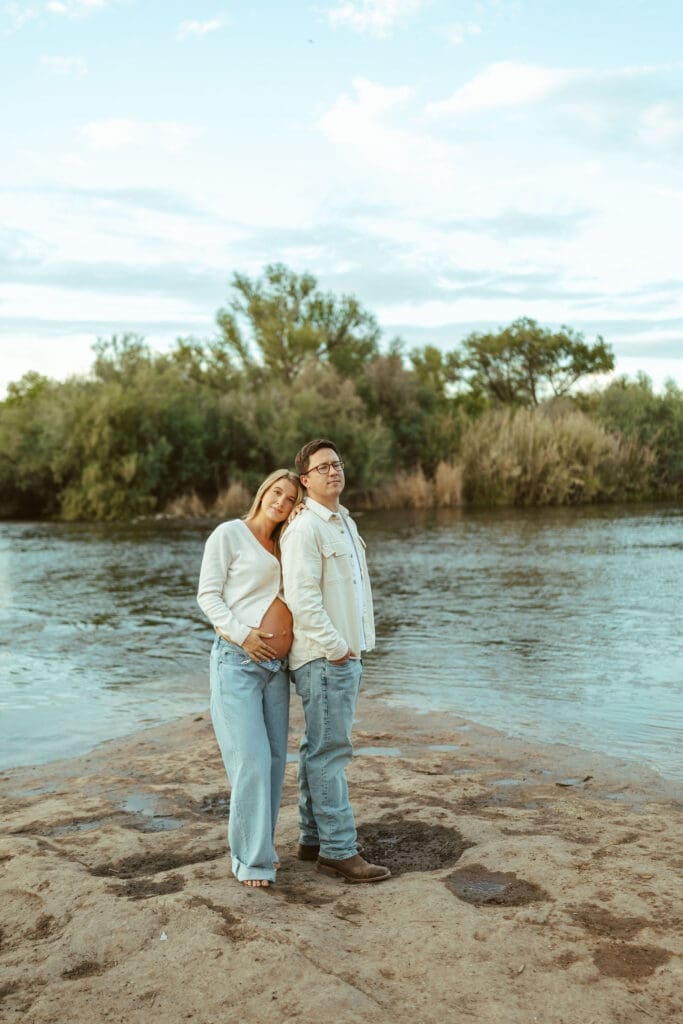 Candid maternity portrait of expecting parents smiling together near the Salt River in Mesa Arizona.