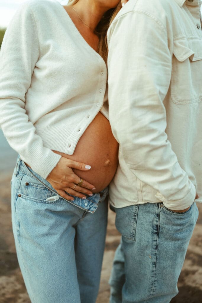 Intimate maternity photo showing close-up baby bump pose beside the river during sunset in Arizona.