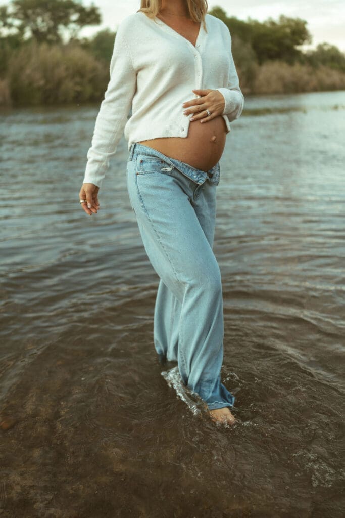 Artistic maternity portrait of expecting mother standing in the river during sunset near Mesa Arizona.