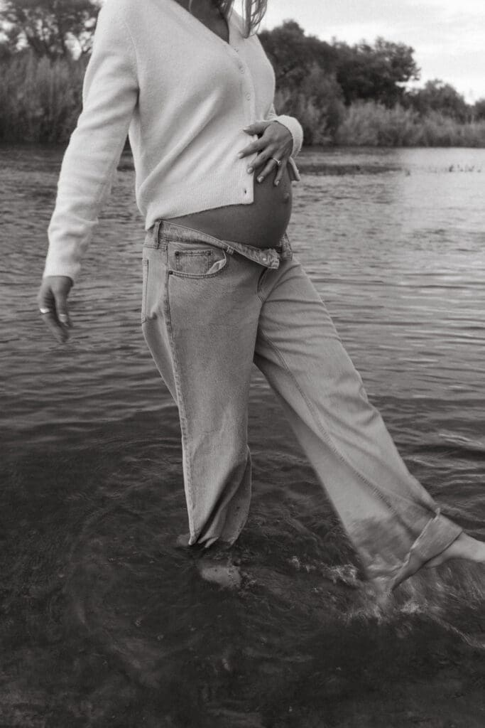 Artistic maternity portrait with motion blur of expecting mother walking through water at the Salt River in Arizona.
