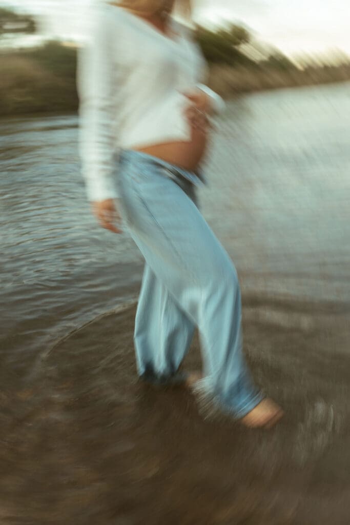 Pregnant woman walking barefoot through the Salt River during a dreamy maternity session in Mesa Arizona.