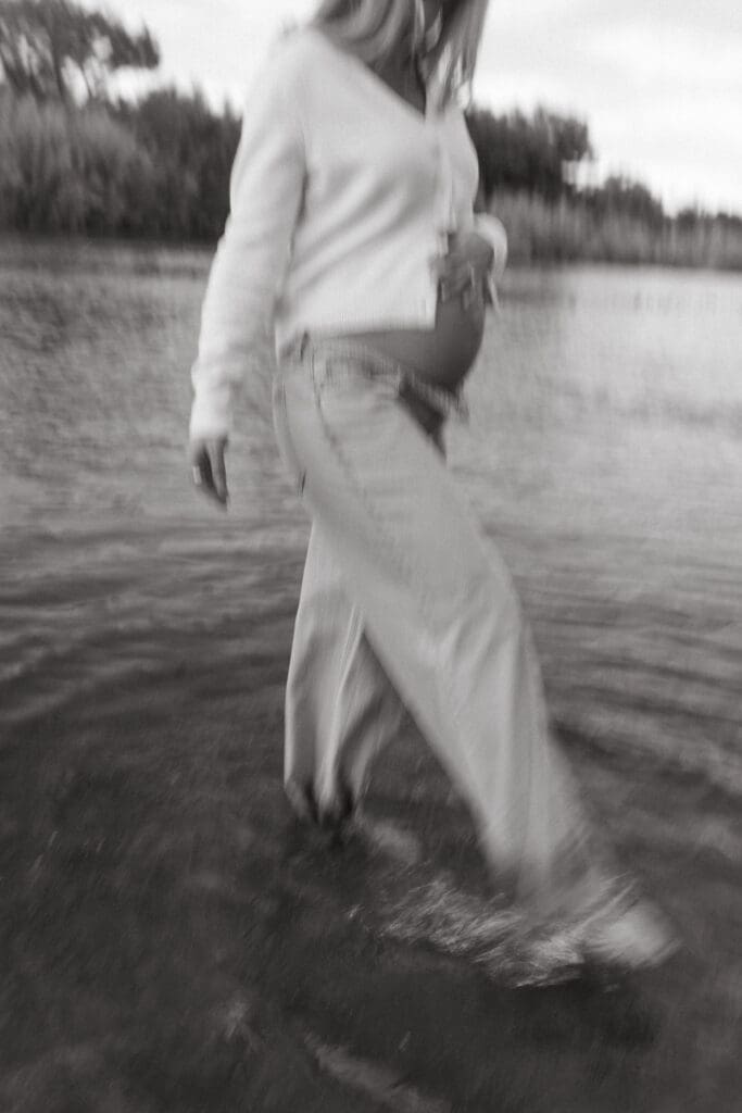 Black and white maternity photo of pregnant woman walking through the Salt River during sunset near Phoenix Arizona.