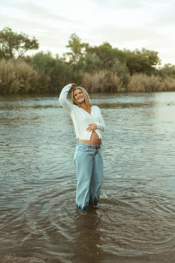 Maternity photography at the Salt River featuring casual neutral styling and water reflections at sunset.