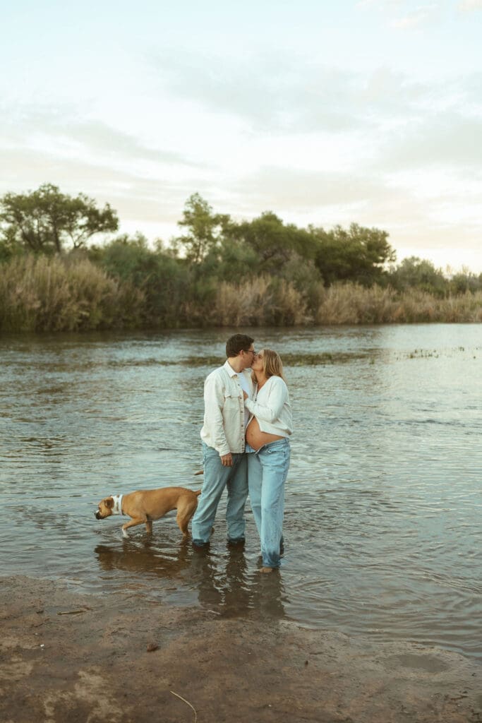 Couple standing in the Salt River with their dog during a maternity session near Mesa Arizona.