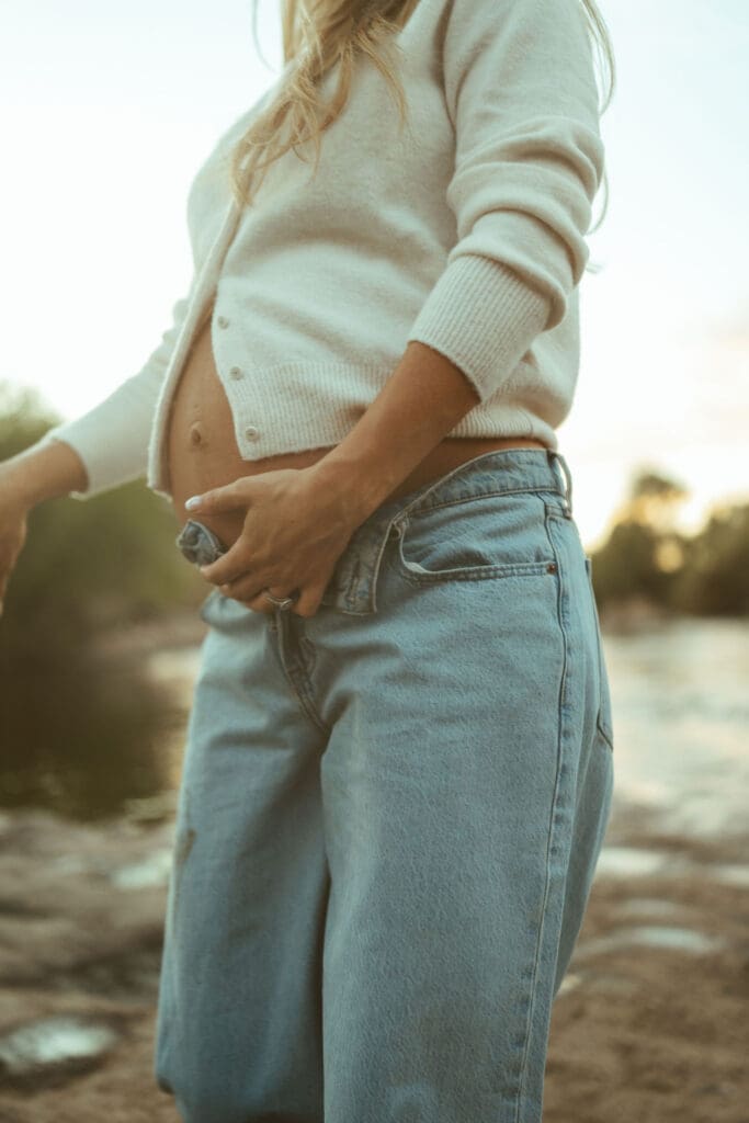 Pregnant woman holding baby bump during an outdoor maternity session at the Salt River near Phoenix Arizona.