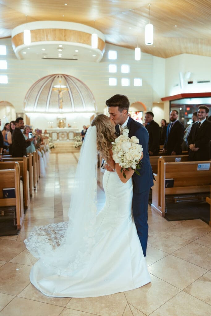 Bride and groom sharing first kiss during Catholic ceremony in Scottsdale Arizona