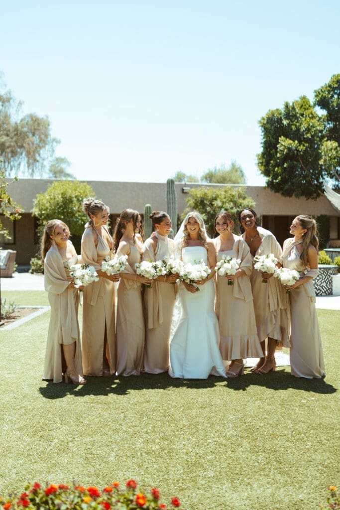 Bride surrounded by bridesmaids holding white bouquets at The Paseo wedding venue
