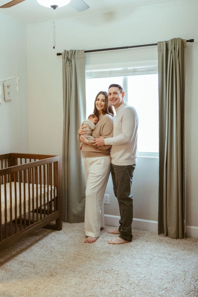 In-home newborn photography in Scottsdale Arizona capturing newborn baby sleeping peacefully in cream knit outfit during natural lifestyle newborn session