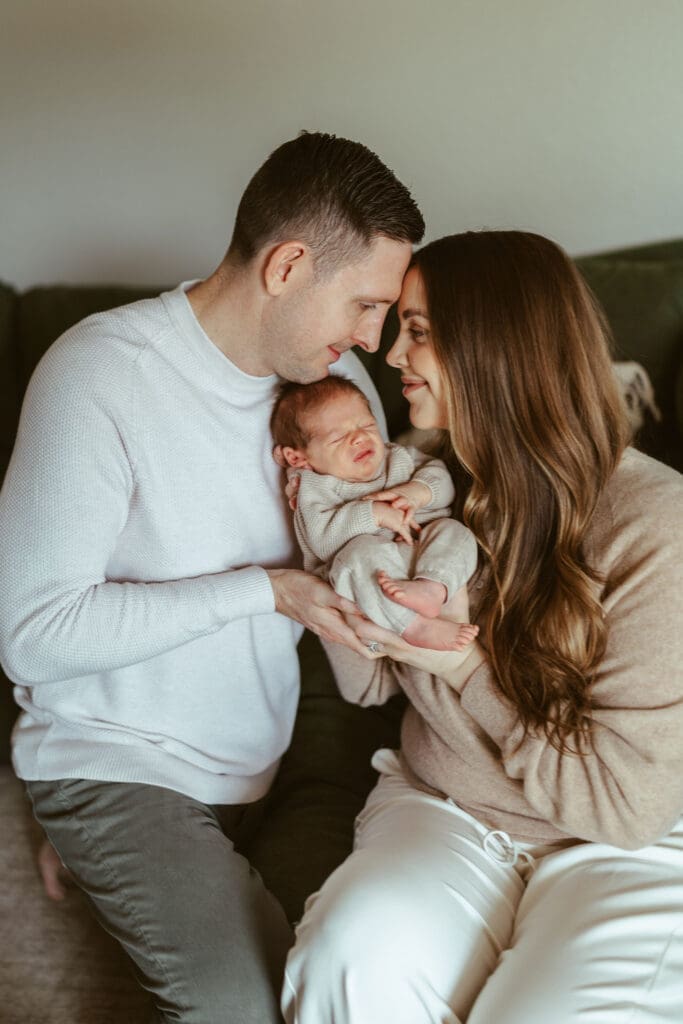 Scottsdale newborn photography with parents holding sleeping newborn baby during relaxed in-home newborn session near Mesa and Tempe Arizona