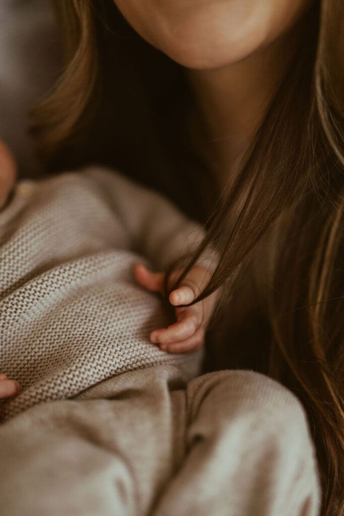 Natural in-home newborn photography in Scottsdale AZ featuring newborn baby wrapped in neutral knit outfit during relaxed lifestyle newborn session