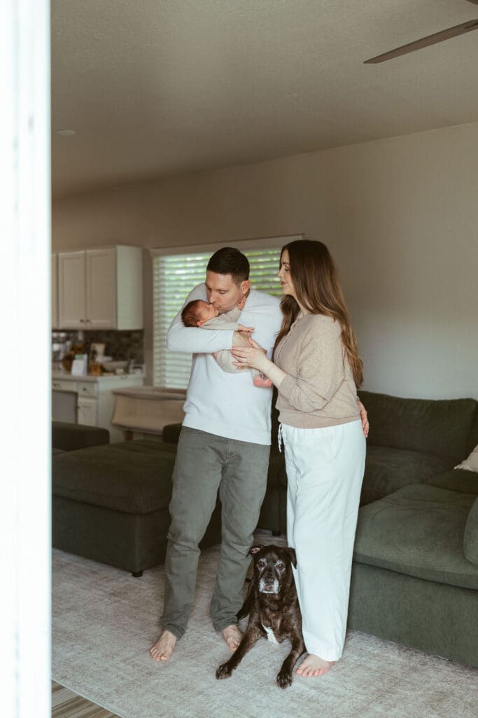 Lifestyle newborn photography in Scottsdale AZ featuring new parents with newborn baby and family dog inside modern Arizona home near Gilbert and Chandler
