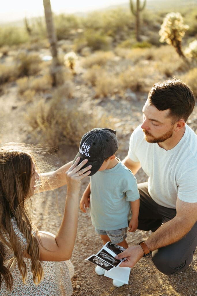 Phoenix Arizona family photographer capturing parents kissing their son during desert maternity session