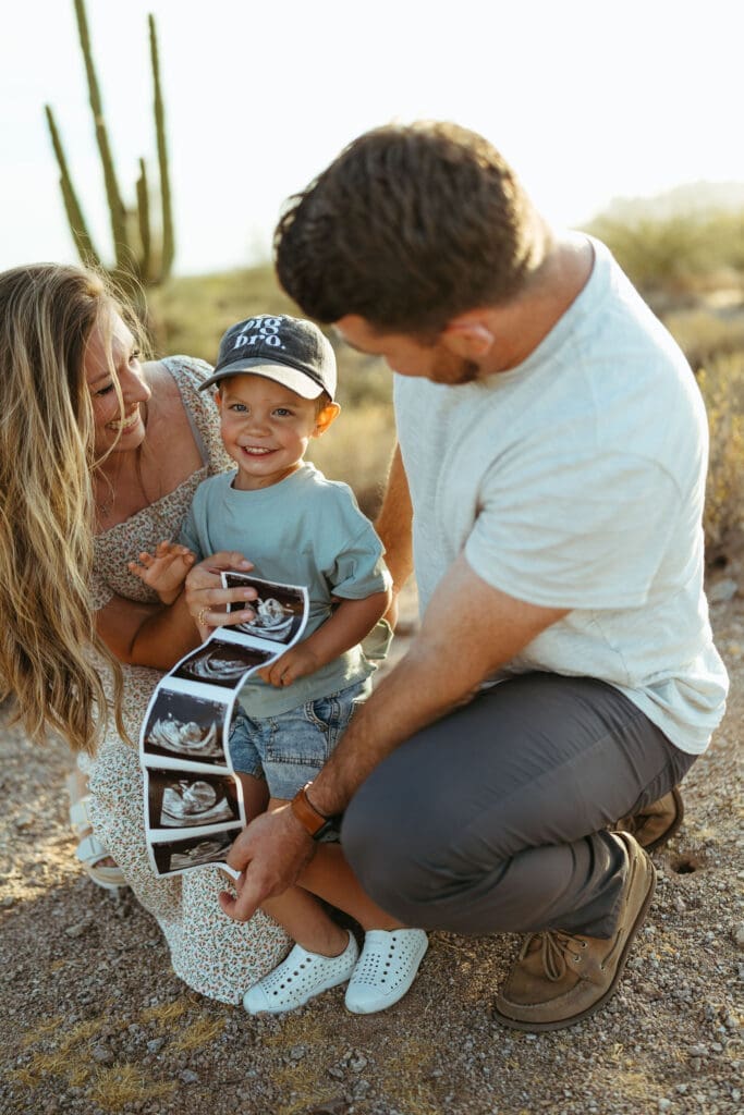 Family holding ultrasound photos during pregnancy announcement session in Apache Junction Arizona