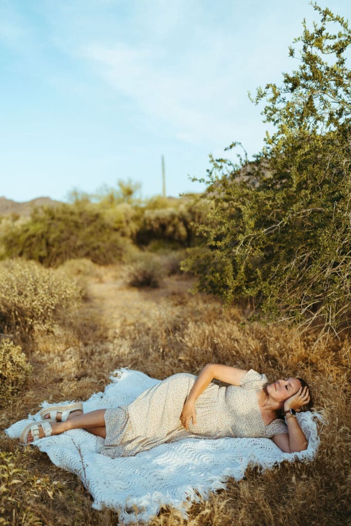 Desert maternity session in Apache Junction Arizona with expecting mother lying on blanket at sunset