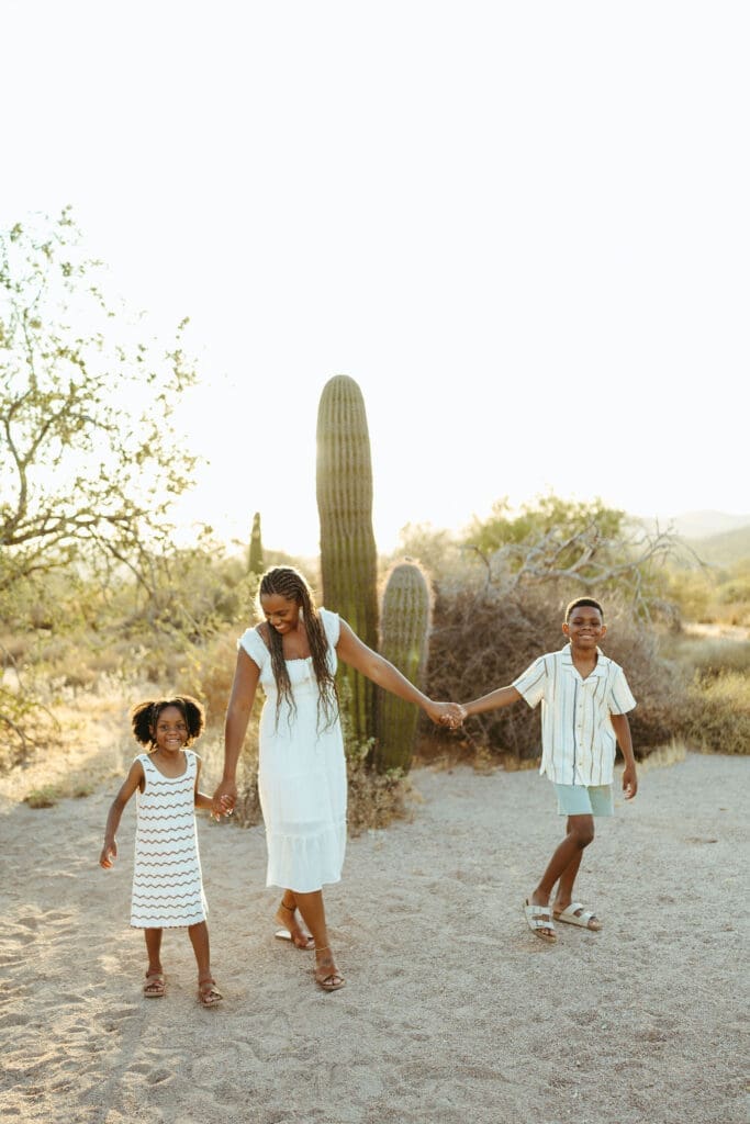 Family walking hand in hand through the Arizona desert with a saguaro cactus in the background