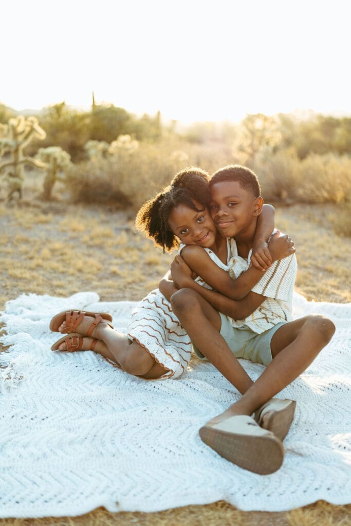 Family cuddling together on a blanket during a sunset family photo session near the Superstition Mountains in Arizona