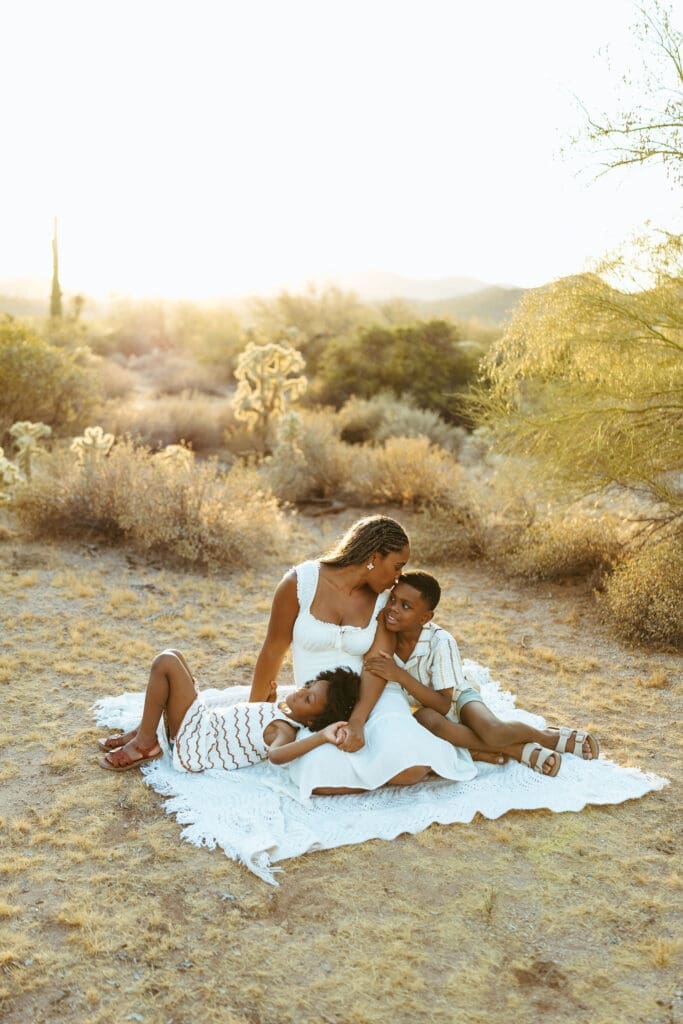 Mother sitting with her children on a blanket during a golden hour family photography session in the Arizona desert